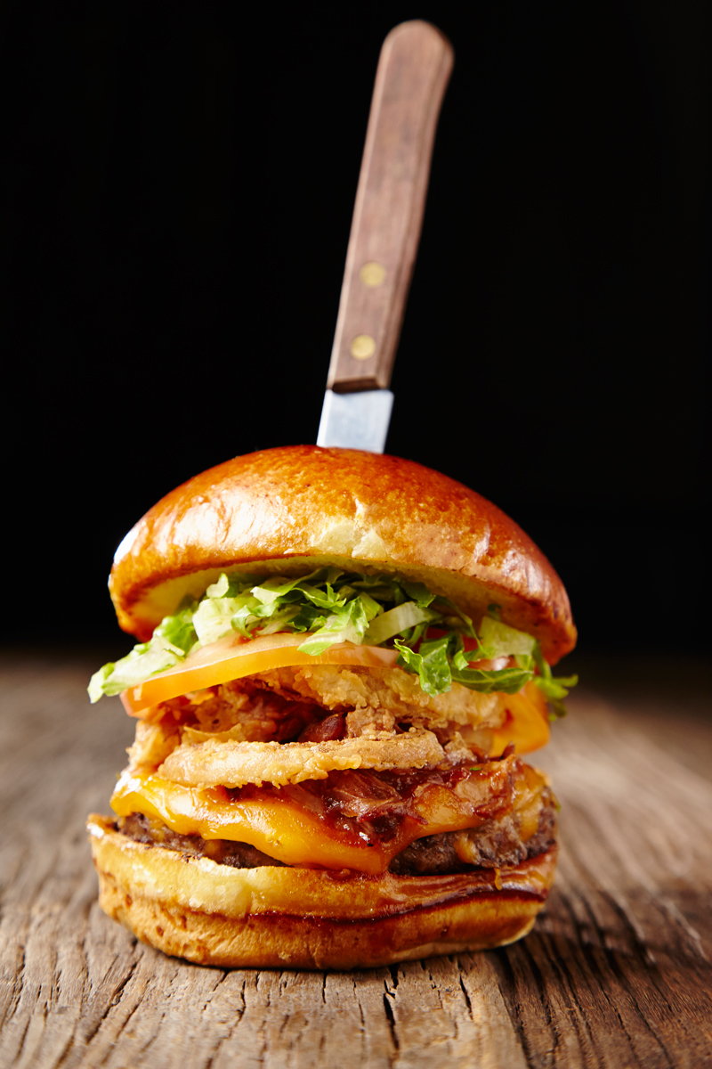 Cheddar burger with bacon, onion rings, tomato, lettuce. Photo by Chris Kessler Photography.  Chris Kessler is a freelance Photographer based in Milwaukee Wisconsin. Specializing in Food photography and portraiture.